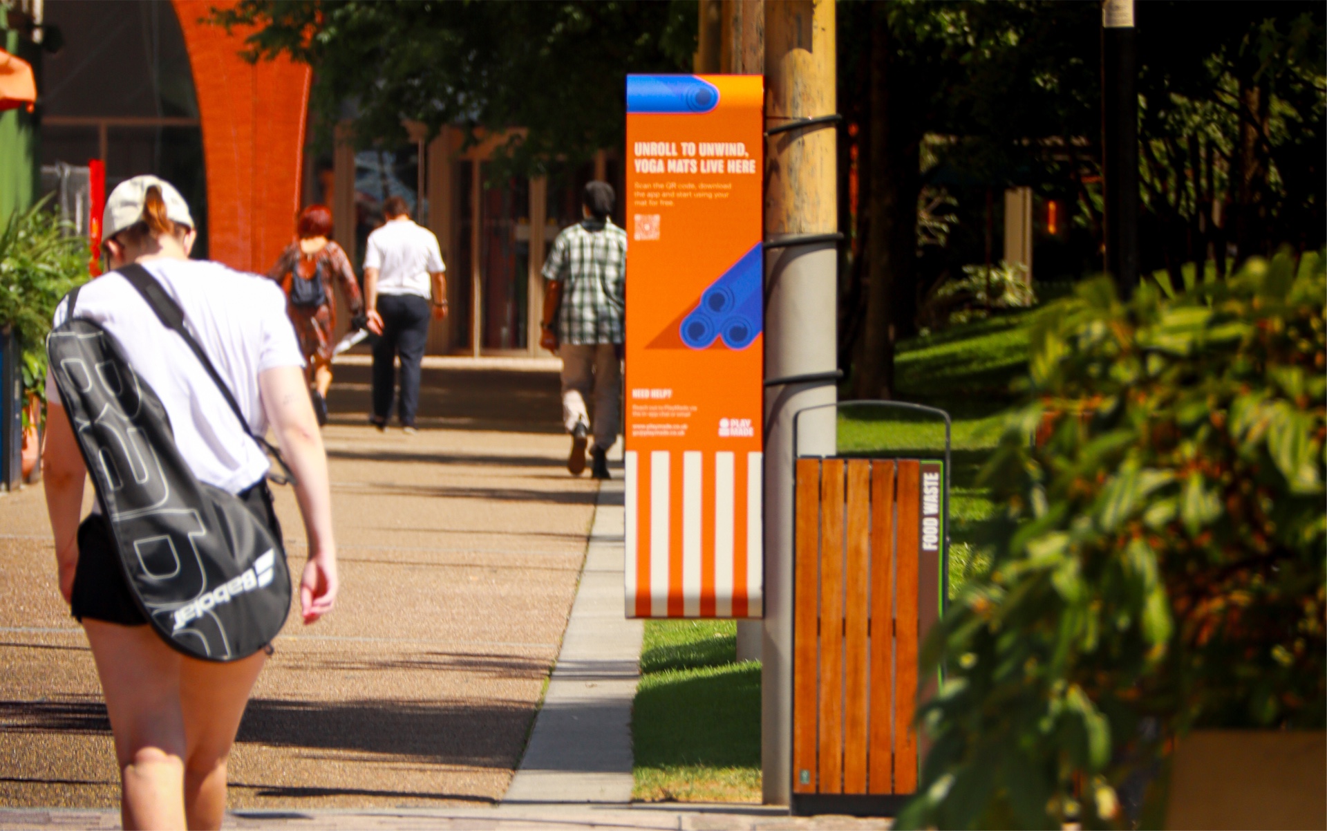 Woman walking past a PlayMade yoga mat pod